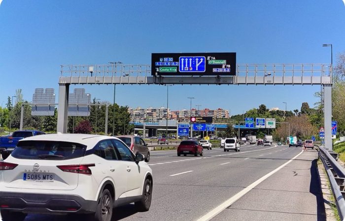 Panel PMV Full Matrix LED instalado sobre pórtico en autopista urbana, mostrando señalización dinámica de carriles y desvíos en tiempo real hacia M-30, A-1 y Costa Rica. Ejemplo de panel de mensaje variable de alta resolución para gestión inteligente del tráfico, seguridad vial y control de movilidad en infraestructuras viarias. Solución de señalización electrónica LED de Fixalia para carreteras y autovías.