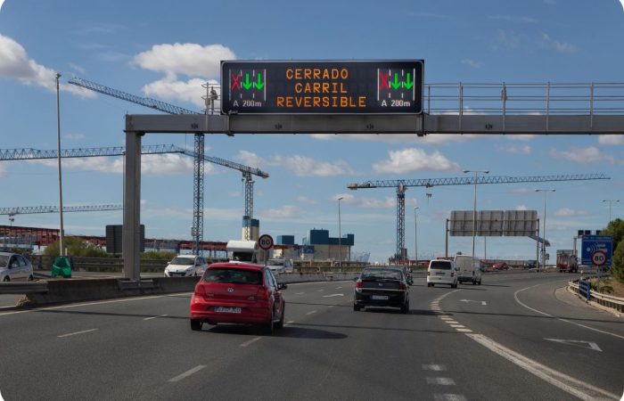 Panel PMV Full Matrix instalado en pórtico sobre autopista indicando “Cerrado carril reversible” con aspas rojas y flechas verdes de regulación dinámica. Sistema avanzado de control de carriles y gestión inteligente del tráfico en tiempo real para reducir congestión y aumentar la seguridad vial en vías de alta capacidad.