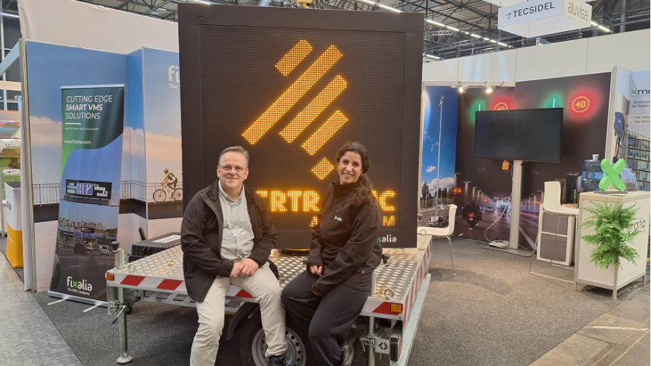 Dos miembros del equipo de Fixalia posando en Intertraffic Amsterdam 2026 delante de un PMV
